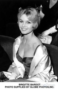 a black and white photo of a woman sitting in a chair wearing a satin dress