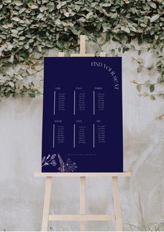 an easel with a seating chart on it in front of a wall covered in ivy