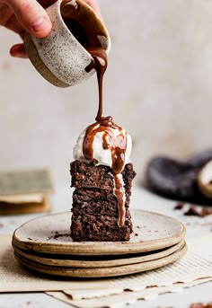 someone pouring chocolate sauce on top of a piece of cake