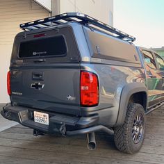 the back end of a gray truck parked in front of a building