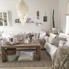 a living room filled with lots of white furniture and decor on top of wooden tables