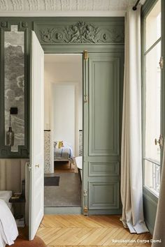 an open door leading to a bedroom with green painted walls and wood floors, along with white curtains