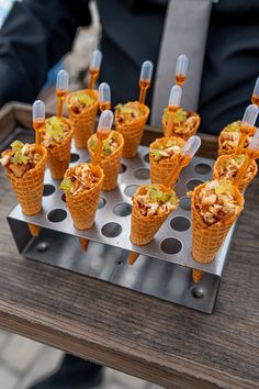 there are many ice cream cones with toppings in them on a tray that is sitting on a table