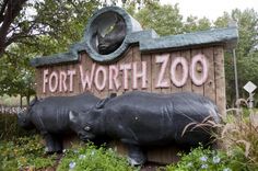 a sign that says fort worth zoo with two rhinoceros in front of it