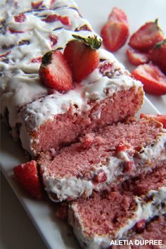 a piece of strawberry cake with icing and strawberries on the top is sitting on a plate