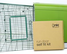 a green box sitting next to a metal cage with a door on the outside and inside