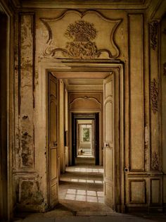 an empty hallway with sun shining through the doors and windows on either side of it