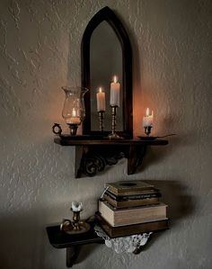 a shelf with books and candles on it in front of a mirror that is reflecting the wall