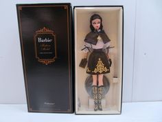 a barbie doll in a black and white dress with gold accents is in a box