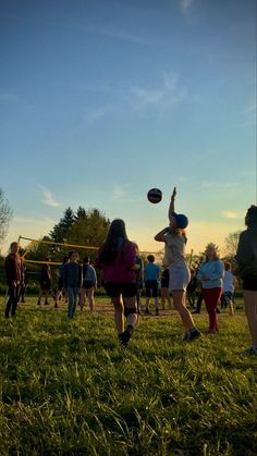 some people are playing frisbee in the grass and one person is reaching up to catch it