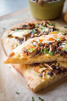 two pieces of flat bread with mushrooms and cheese on it sitting on a cutting board