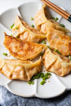 some dumplings are on a white plate with chopsticks