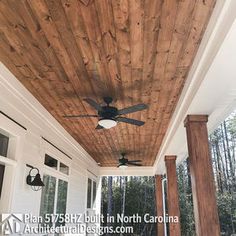 a ceiling fan on the outside of a porch with wood planks and white siding