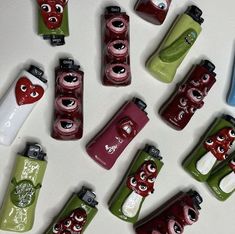 many different types of lighters with eyes and mouths painted on them, all lined up in the same pattern