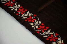 a red and white flowered design on a black fabric with silver thread trimming