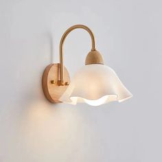 a wall light with a wooden arm and white glass shade on the back of it