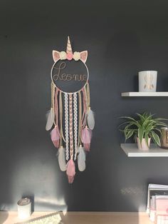 a wall hanging with a unicorn head and name on it, next to a potted plant