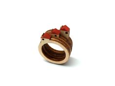 a wooden ring with two houses on top and one red roof in the middle, against a white background