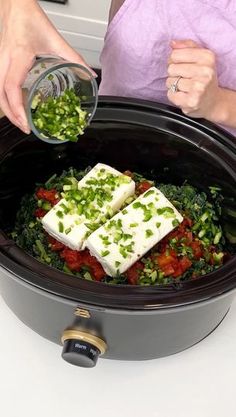 a woman is pouring something into a crock pot filled with vegetables and tofu