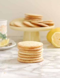 a stack of cookies sitting on top of a table next to a plate with lemons