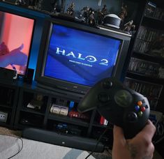 a person holding a game controller in front of two televisions