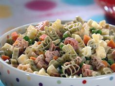 a white bowl filled with pasta salad on top of a blue and white polka dot table cloth