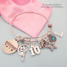 a silver bracelet with charms on it and a pink satin bag in the back ground