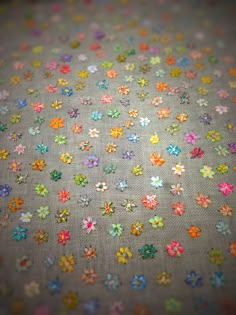 multicolored flowers are scattered on a gray fabric with tiny dots in the center