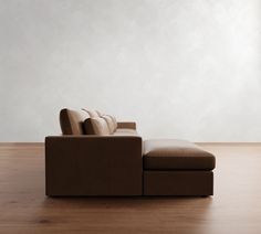 a brown couch sitting on top of a wooden floor next to a white wall in an empty room