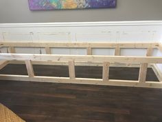 a bed frame sitting on top of a hard wood floor next to a painting hanging above it