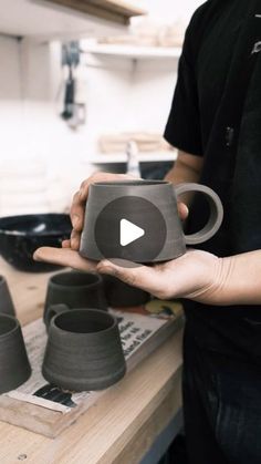 a man holding a cup in his hand while standing next to pots on the counter