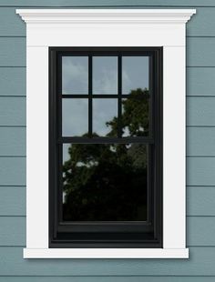 an open window on the side of a blue house with trees in the background and clouds in the sky