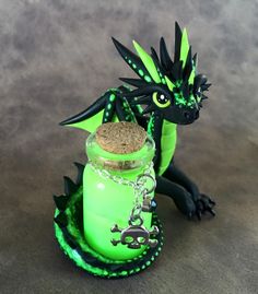 a green dragon figurine sitting on top of a jar with a cork in it