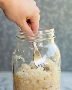 a person is spooning food out of a glass jar with some rice in it