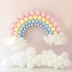 a rainbow made out of balloons sitting on top of a white table next to a wall