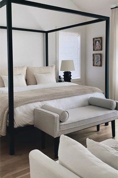 a bedroom with a four poster bed and white furniture in the corner, along with two couches