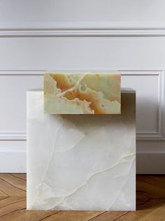 a marble block sitting on top of a hard wood floor next to a white wall