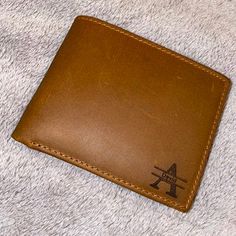 a brown wallet sitting on top of a white blanket