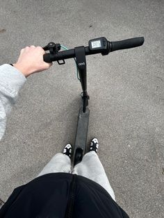 a person riding a scooter with their feet on the handlebars in front of them