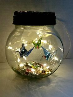 a glass jar filled with lots of different types of origami birds in it