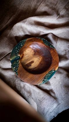 a wooden bowl sitting on top of a bed next to a brown cloth covered floor