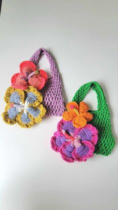 two crocheted flower purses sitting next to each other on a white surface