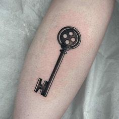 a black and white photo of a key tattoo on the left forearm, with an arrow in the middle