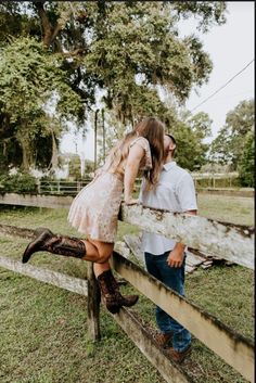 a man and woman leaning on a fence