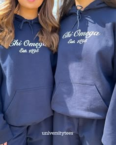 two girls wearing blue hoodies with white writing on them