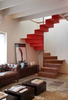 a living room filled with furniture and a red stair case next to a brown couch