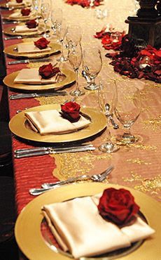 the table is set with gold plates and red roses