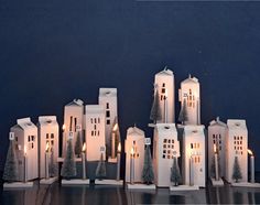 a group of small white buildings with lit candles in front of them on a table