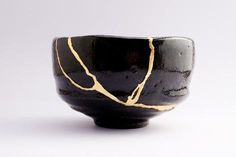 a black and gold ceramic bowl on a white surface with lines drawn across the top