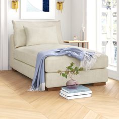 a living room with a white couch and books on the floor